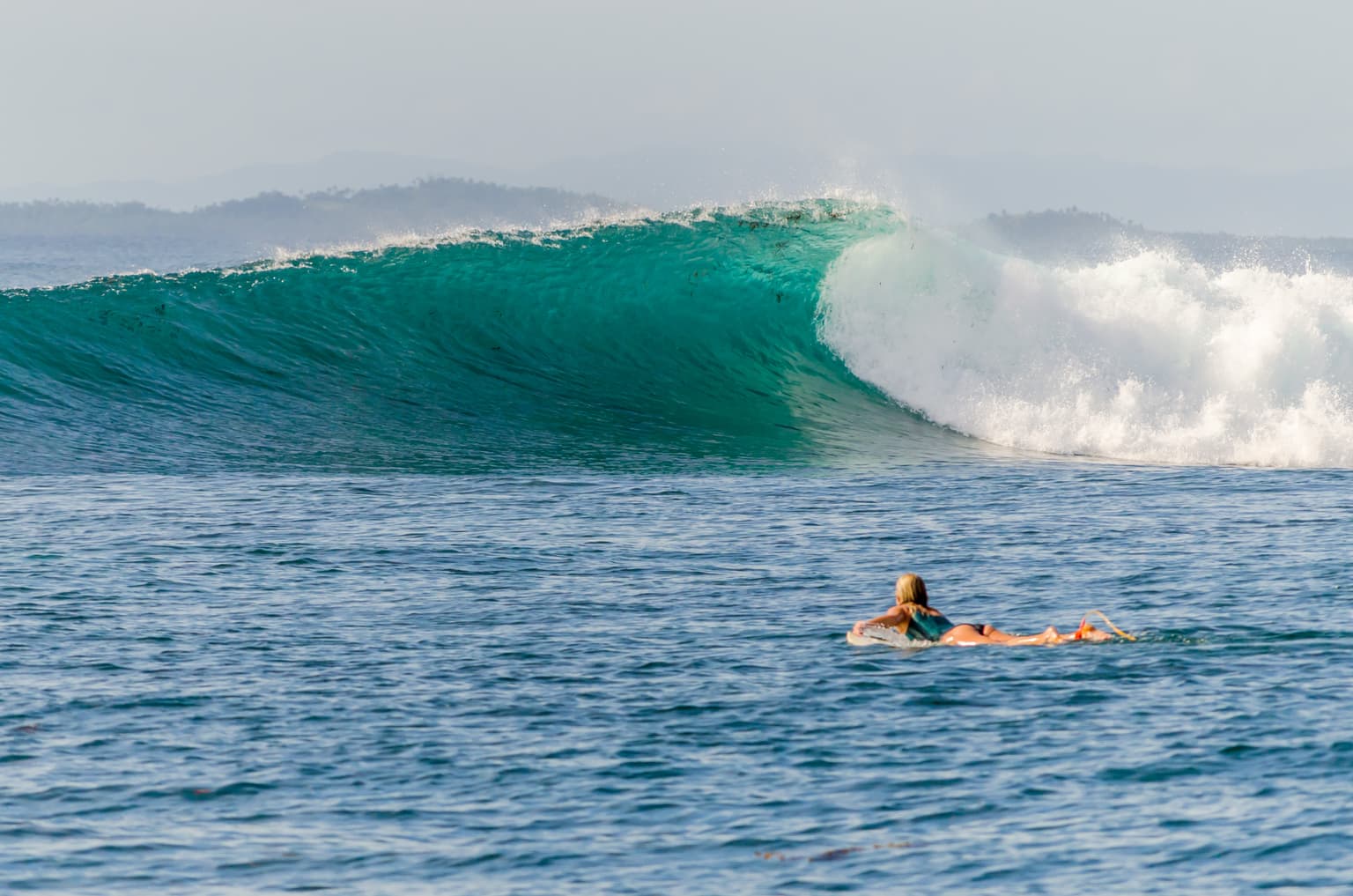 Female surfer paddling out to Pansukyan surf spot in SIargao